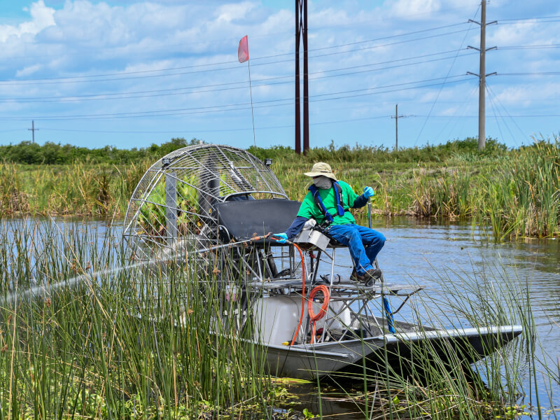 Person on airboat doing Aquatic weed Treatment